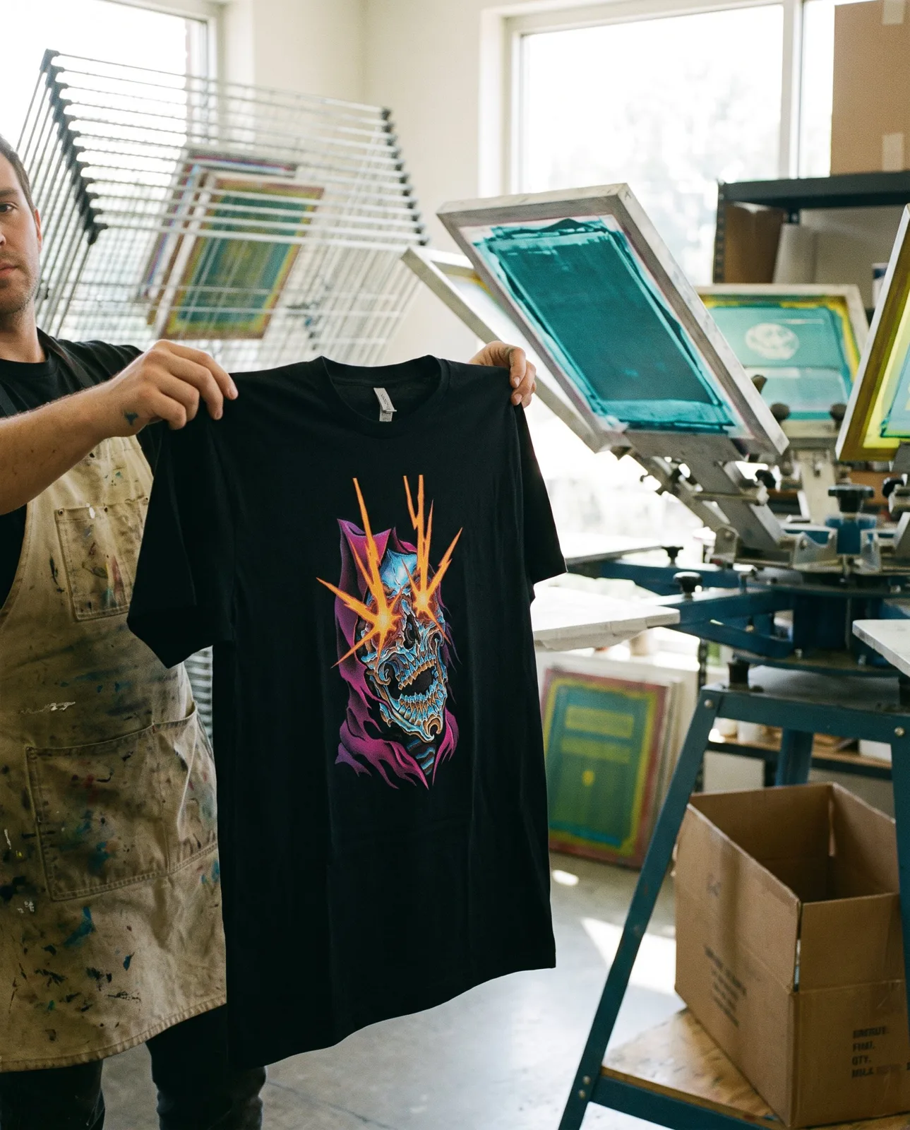 A screen printer holding up a freshly printed t-shirt
